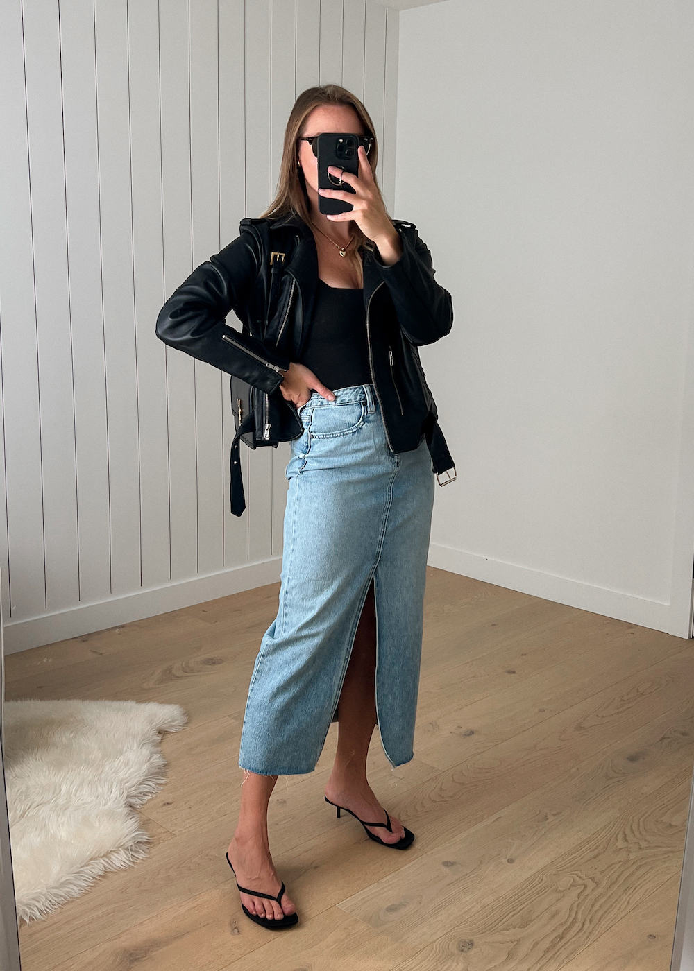 Christal wearing a denim midi skirt with a black tank top and a leather jacket.