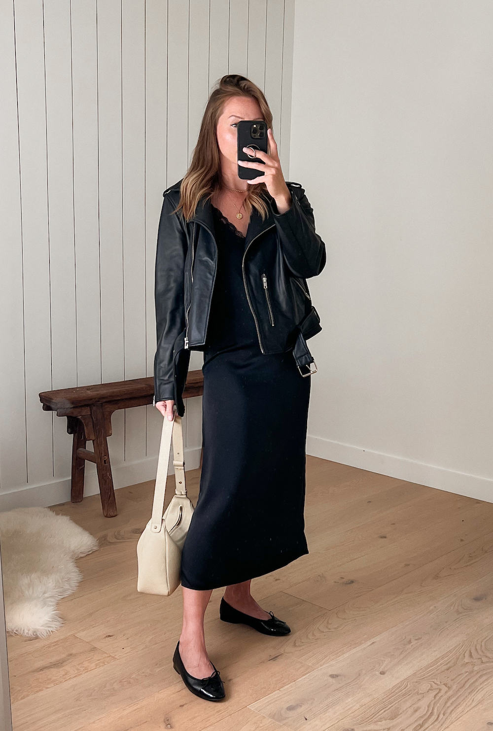 Christal wearing a black slip dress with black ballet flats and a black leather jacket.