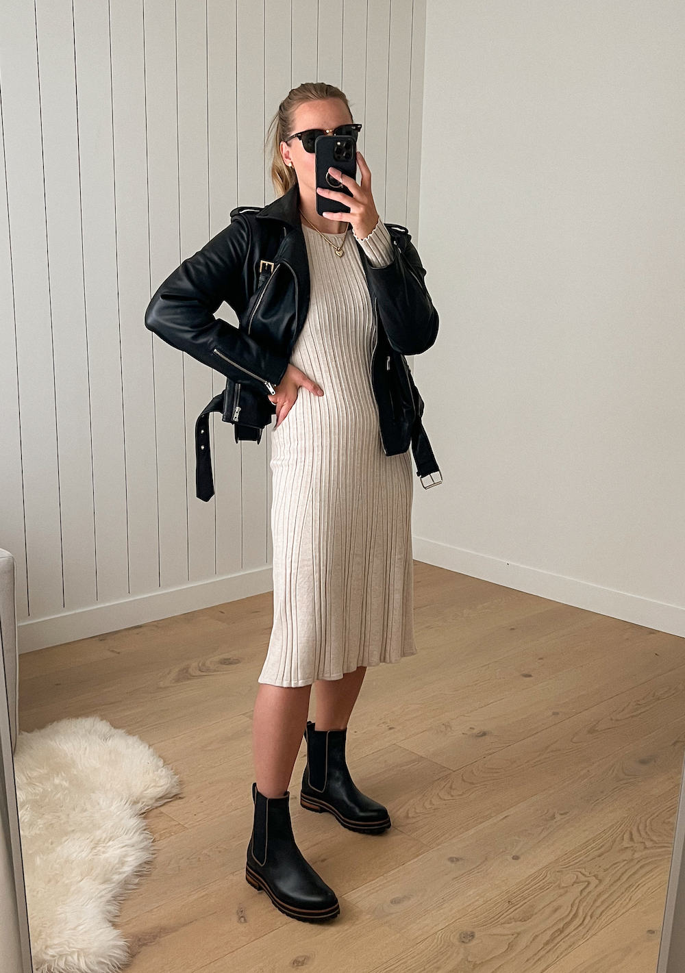 Christal wearing a cream sweater dress with a black leather jacket and Chelsea boots.