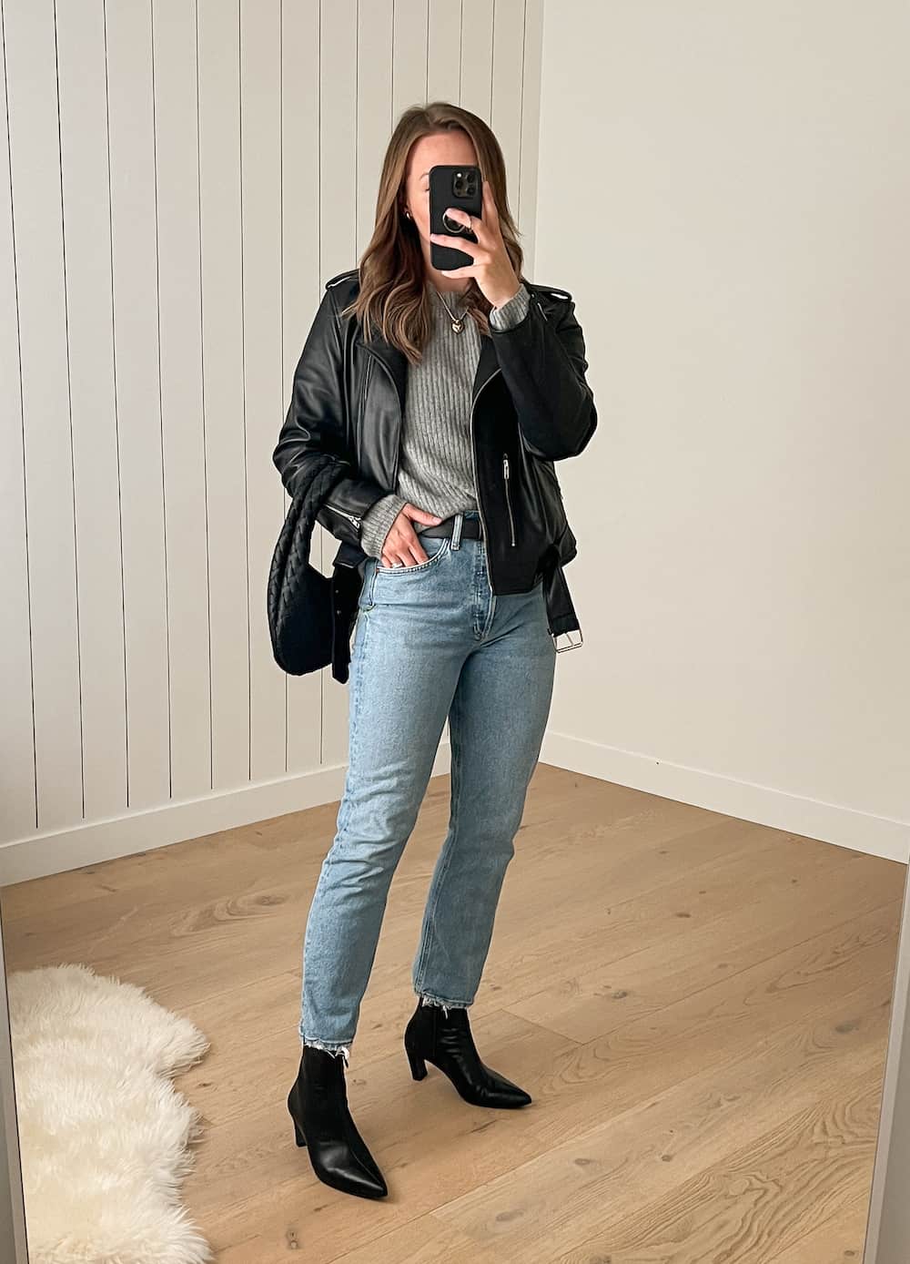 Christal wearing straight jeans with black booties and a grey sweater under a leather jacket.