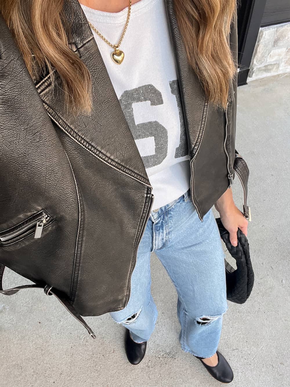 Christal wearing distressed jeans with a graphic tee under a leather jacket.