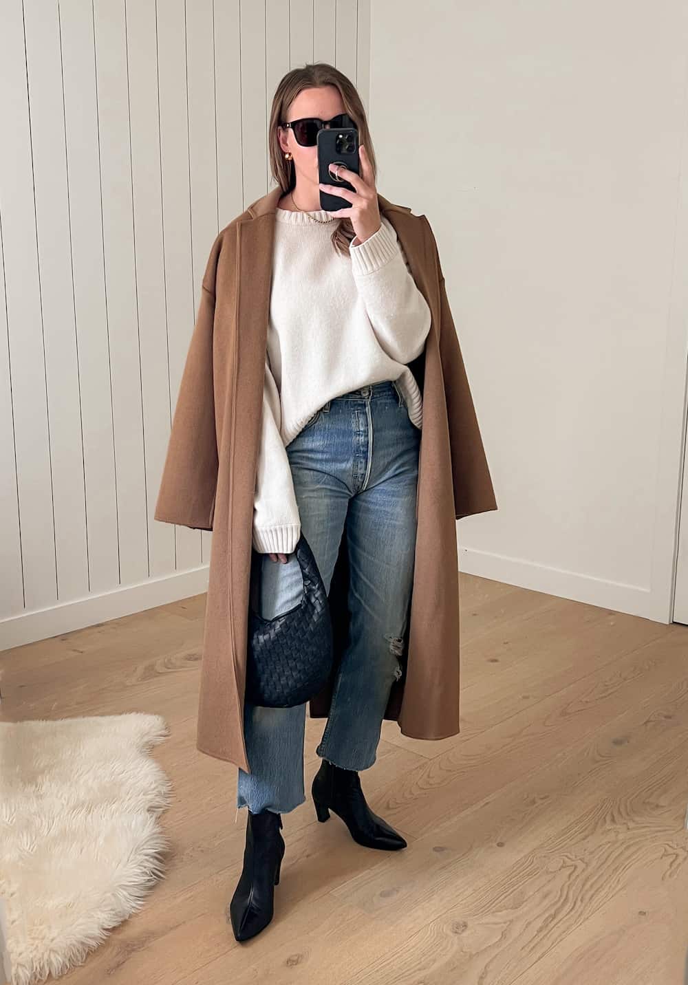 Christal wearing jeans with a white sweater and a brown coat with black booties.