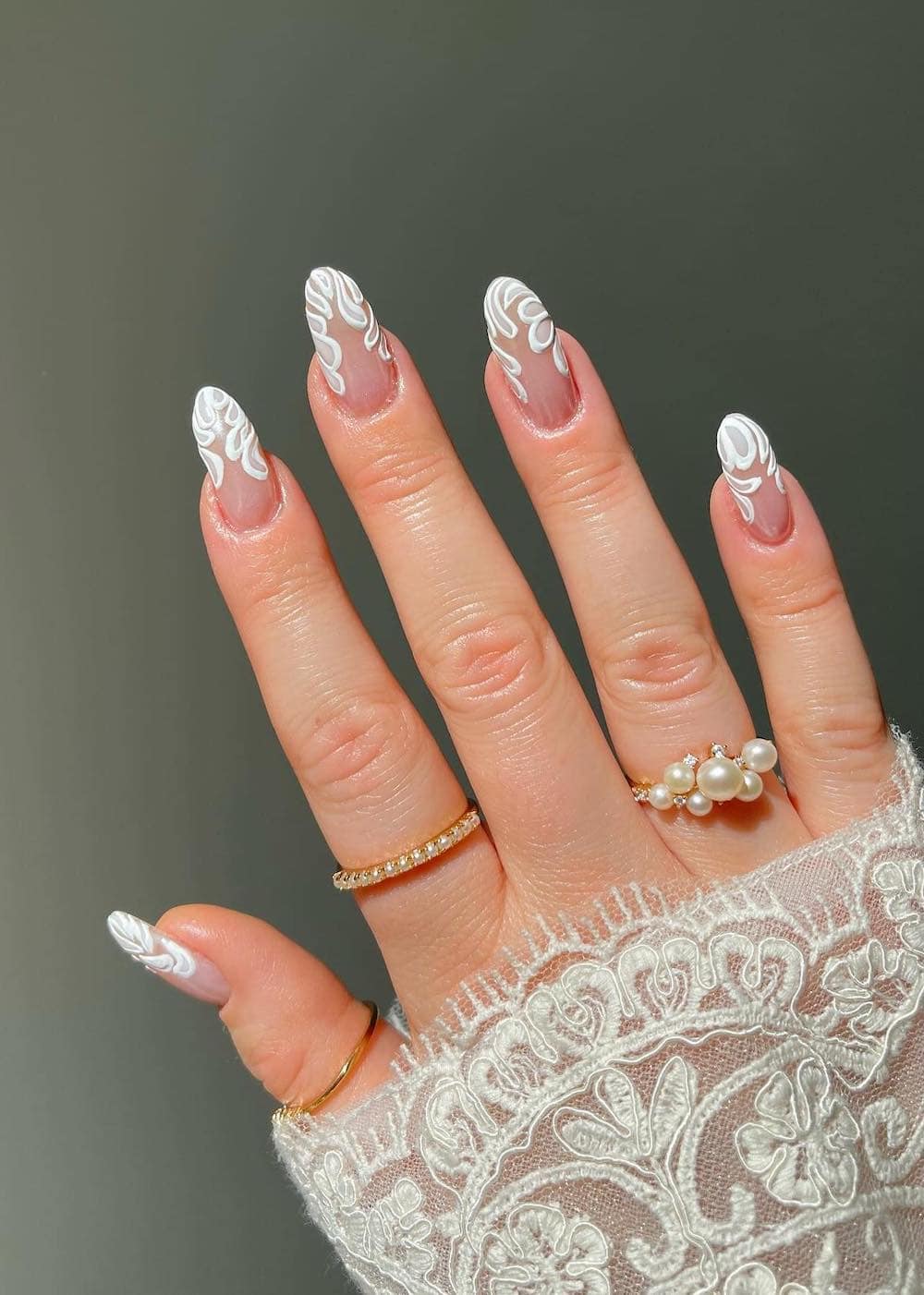 A hand with medium nude almond nails with white petal tips