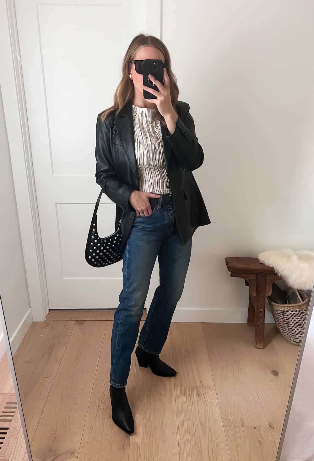 Christal wearing jeans with black booties, a silver top and a black leather blazer.