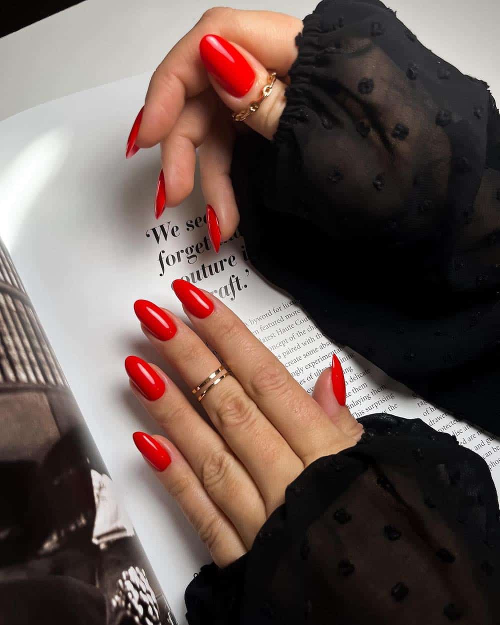 A hand with medium almond nails painted a bright crimson red