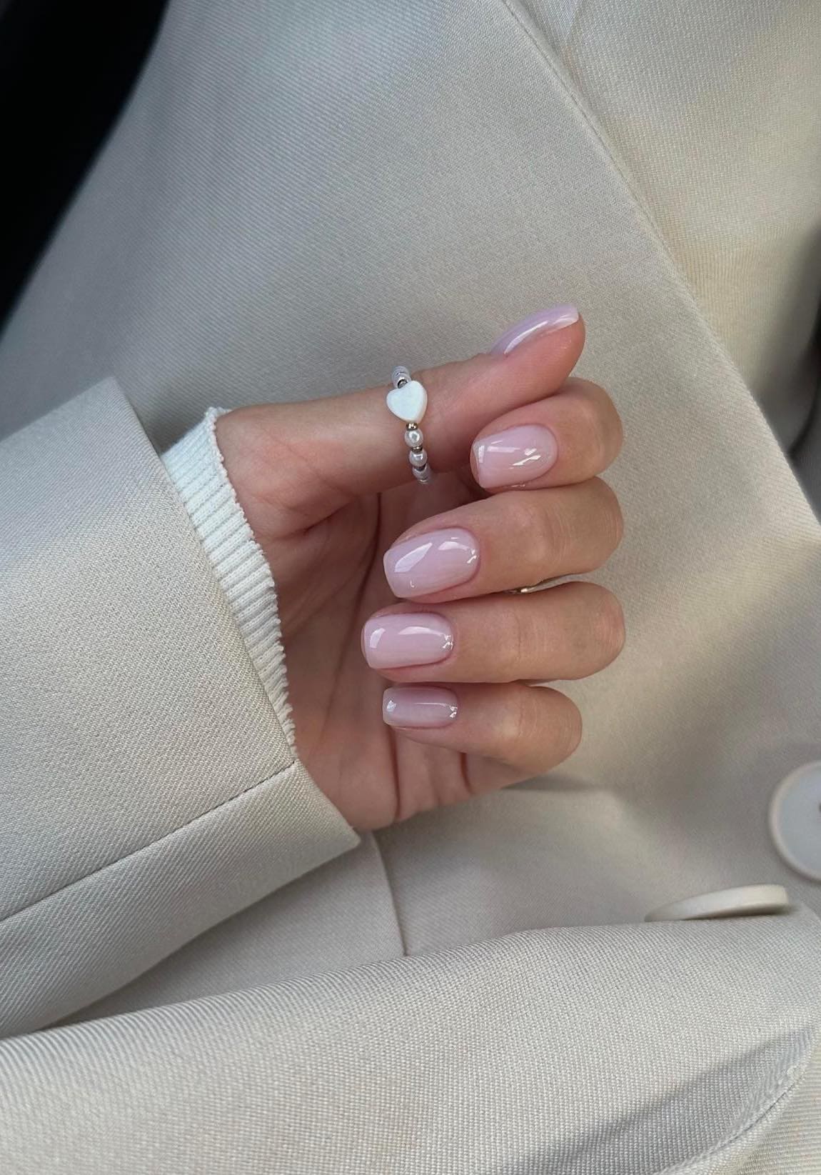 A hand with short soft nude pink nails