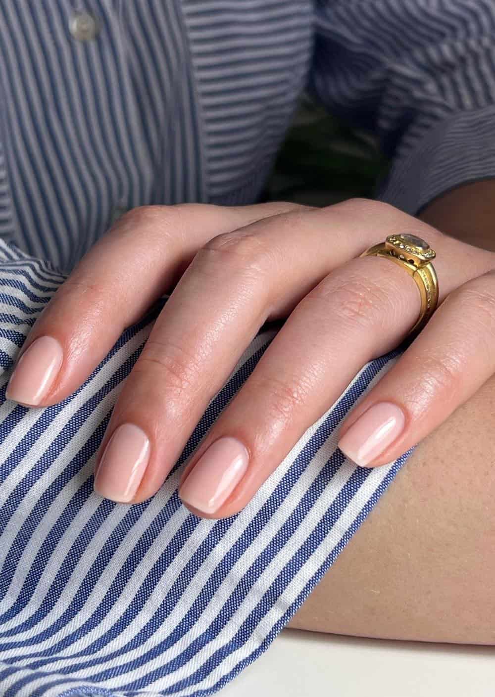A hand with short nude square nails