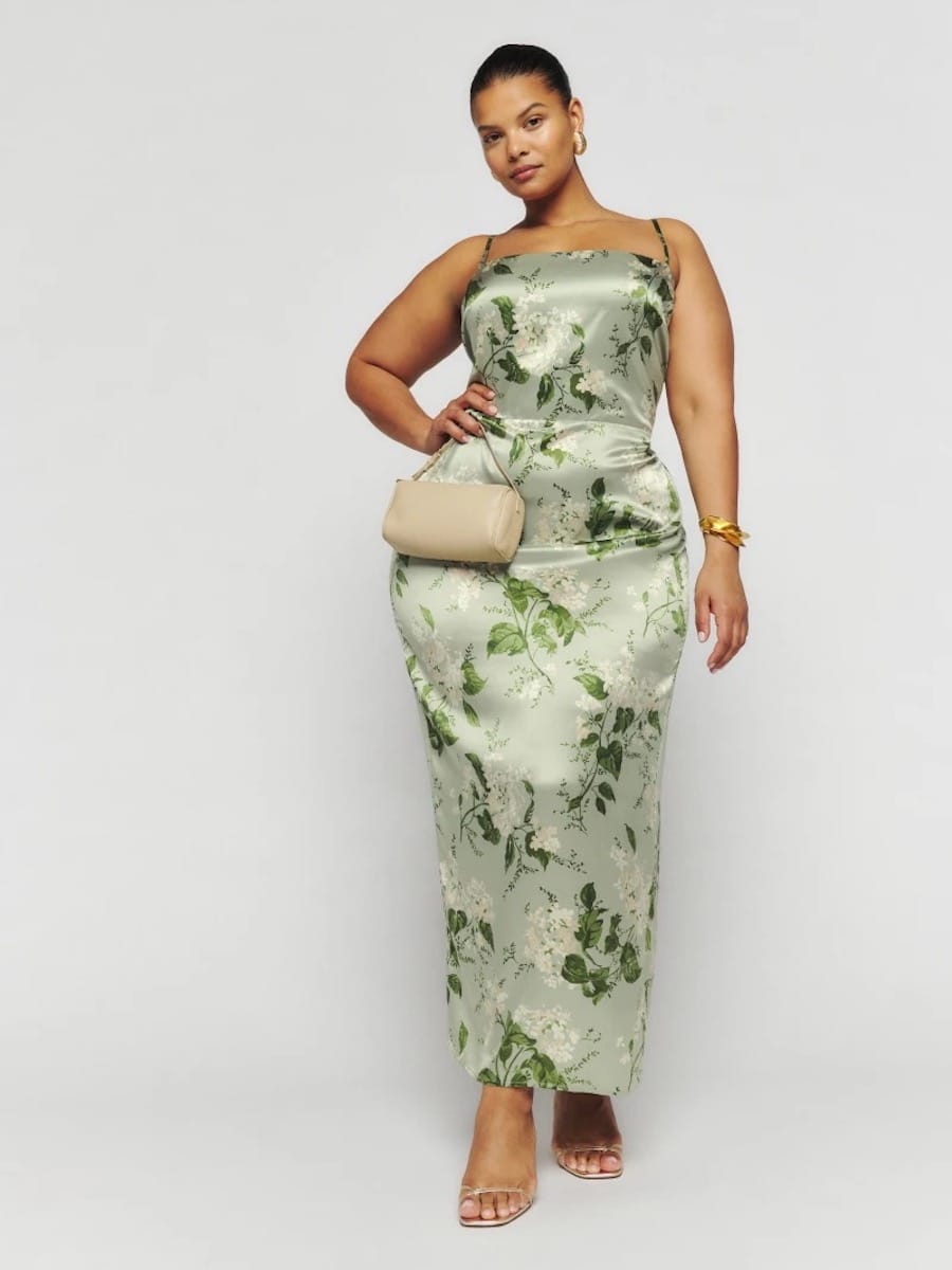 A woman wearing a sleeveless green floral maxi dress with a fitted waist