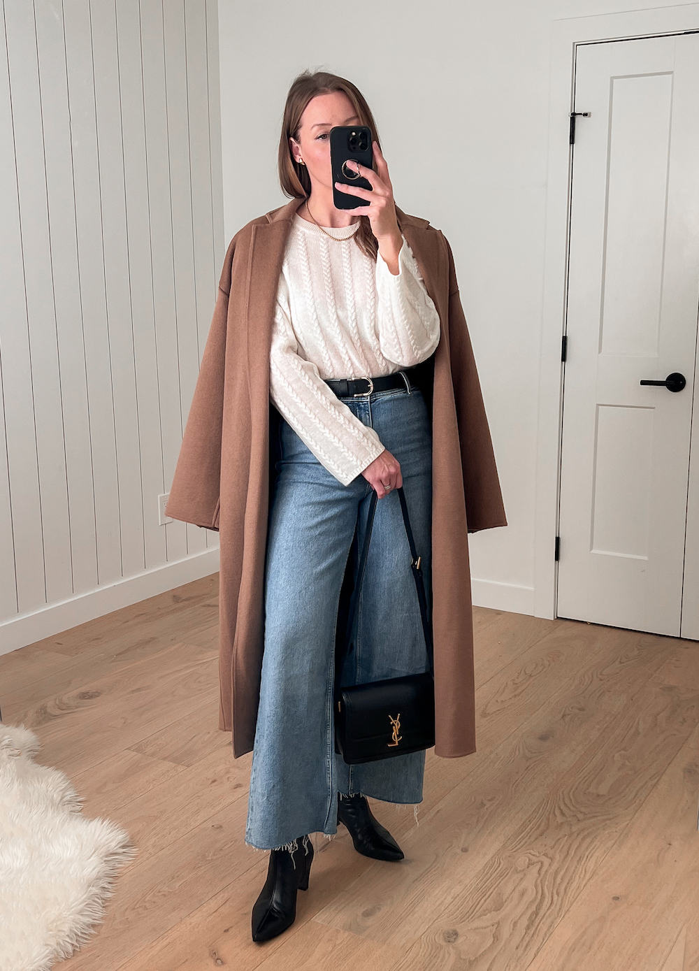 Christal wearing a long denim skirt with a white sweater, black booties and a camel colored coat.