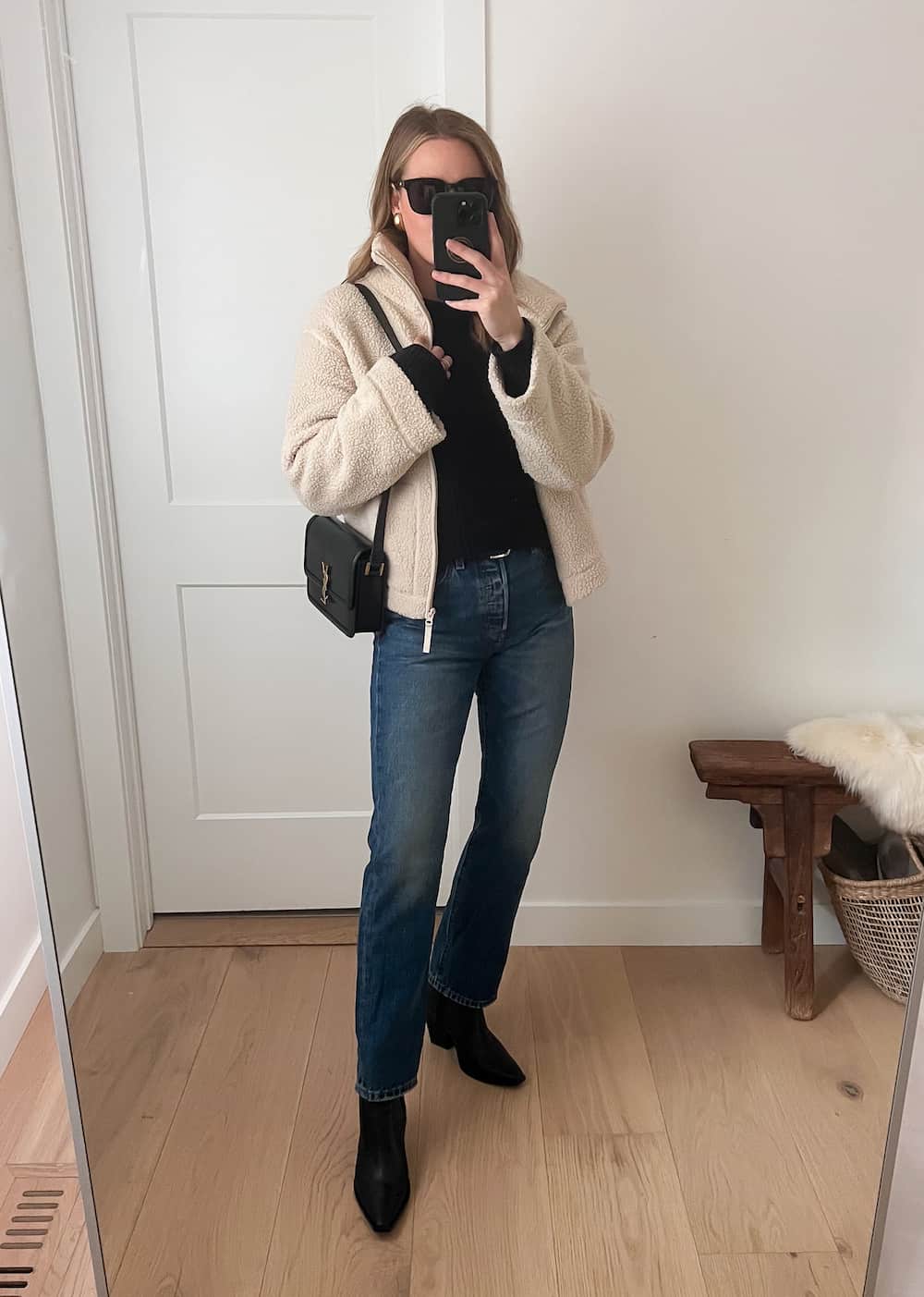 Christal wearing dark denim straight jeans with black booties and a white sherpa jacket.