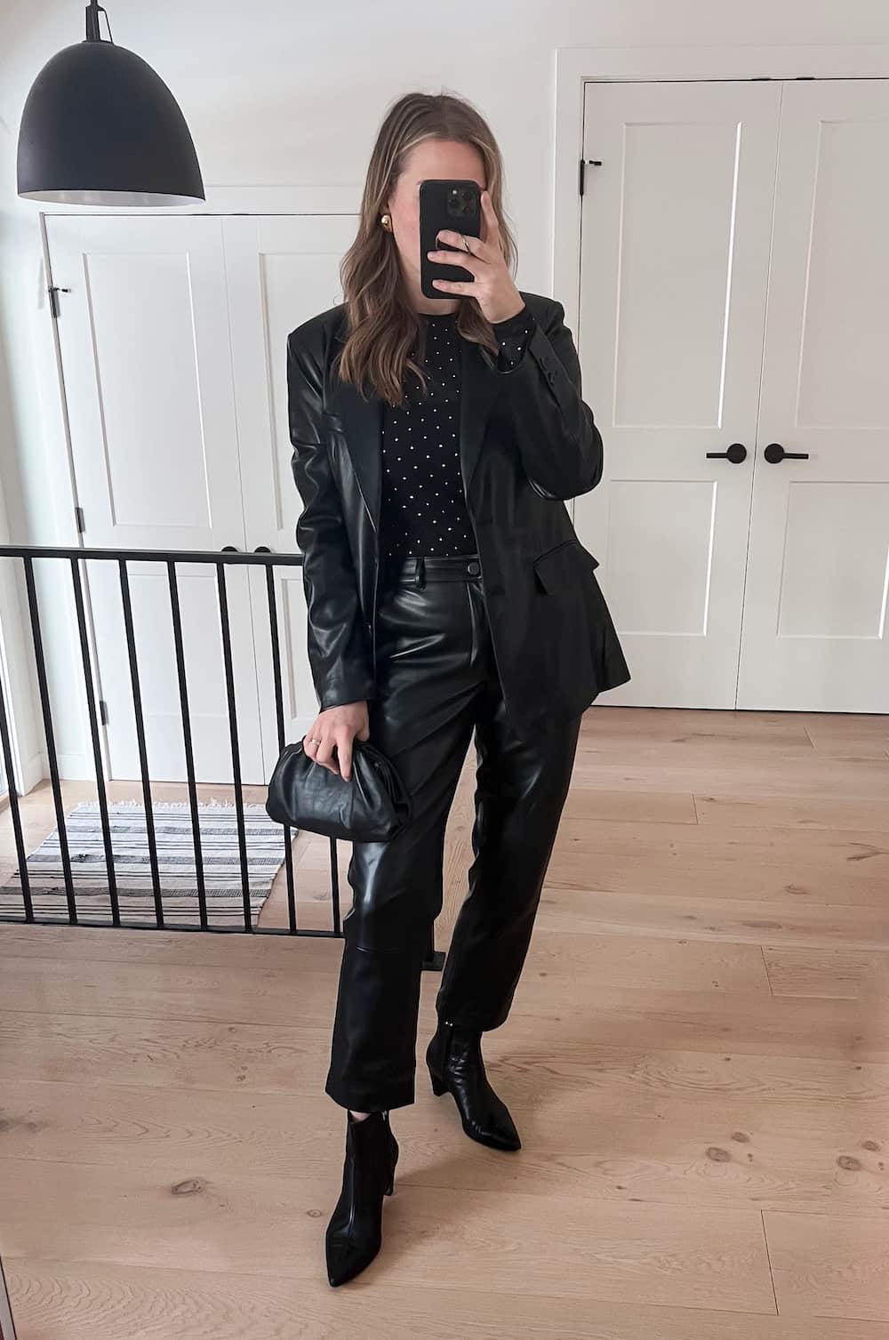 woman wearing a winter going out outfit with a black leather blazer, black top, black leather pants, and black ankle boots