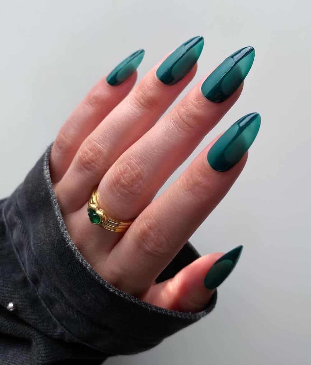 A hand with dark green jelly nails with abstract glossy green details