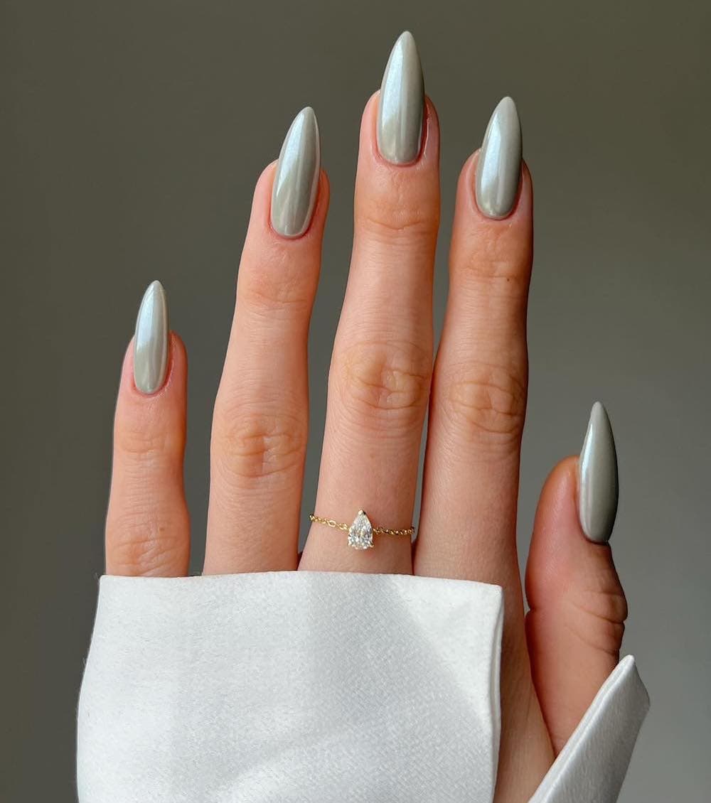A hand with long almond nails painted a dusty chrome shade