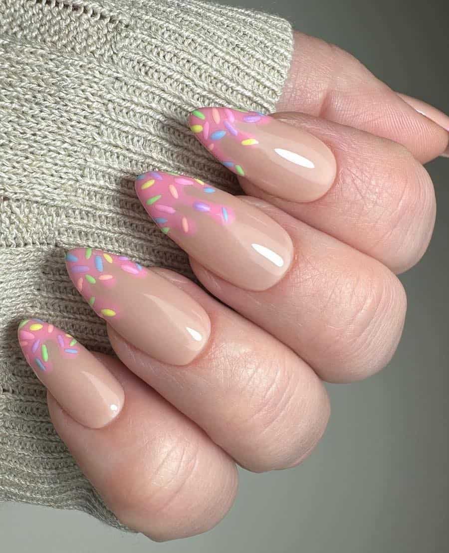 Long nude almond nails with pink melted French tips and colorful sprinkle details