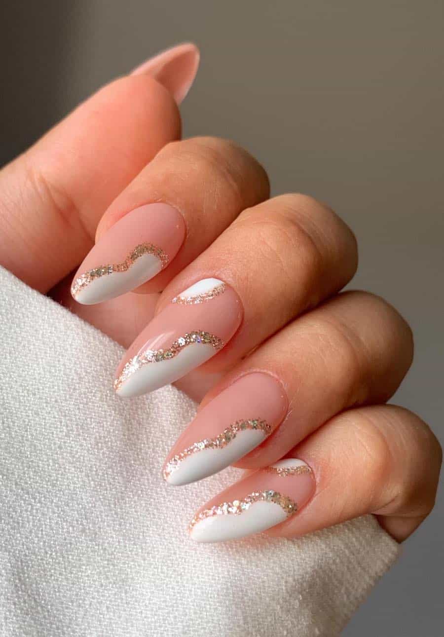 Long glossy nude pink almond nails with white waves with gold glitter borders