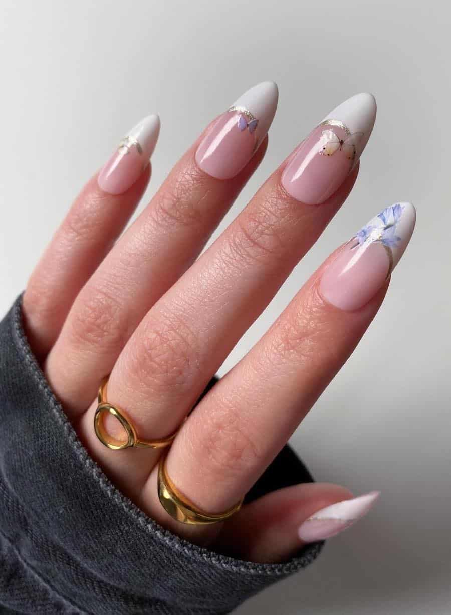 Long glossy nude pink almond nails with white tips, silver borders, and floral and butterfly nail stickers