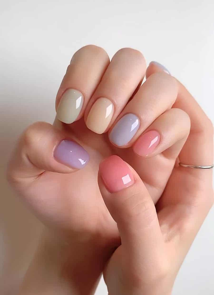 Short squoval nails with pastel rainbow shades and a high-gloss finish