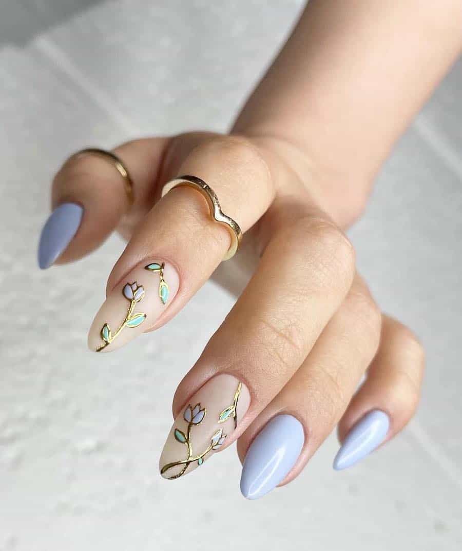 Medium light blue almond nails with two nude accent nails featuring gold outlined flowers