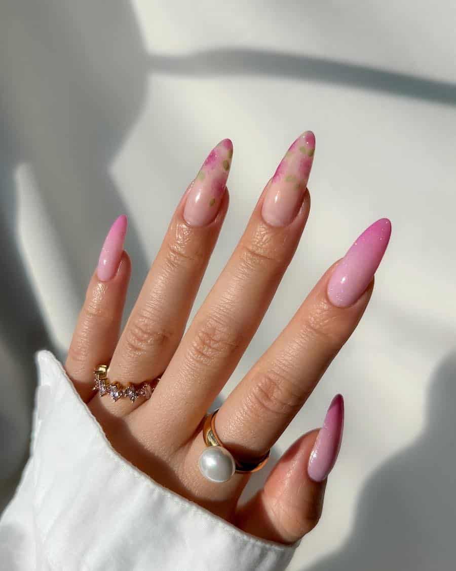 Long almond nails with a white to sparkly pink ombre and two nude accent nails featuring pink floral art