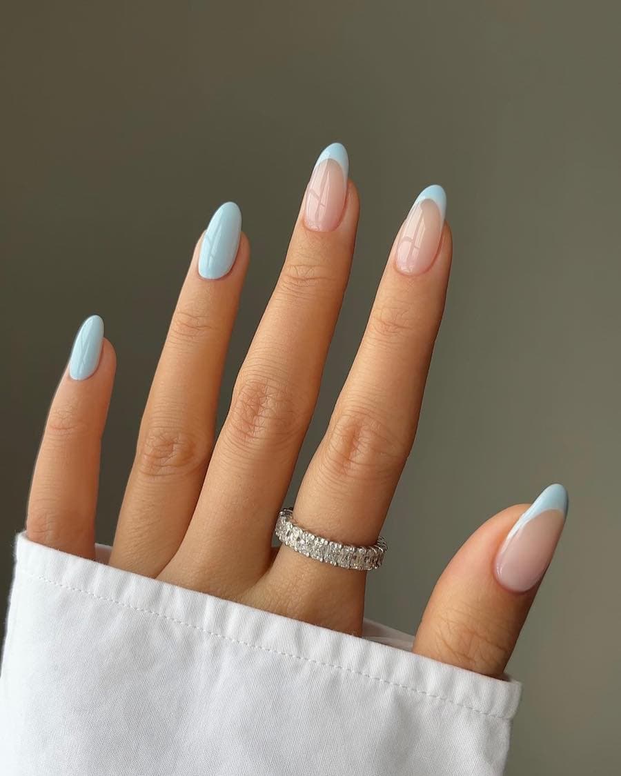 Medium nude almond nails with light blue tips and two solid blue accent nails