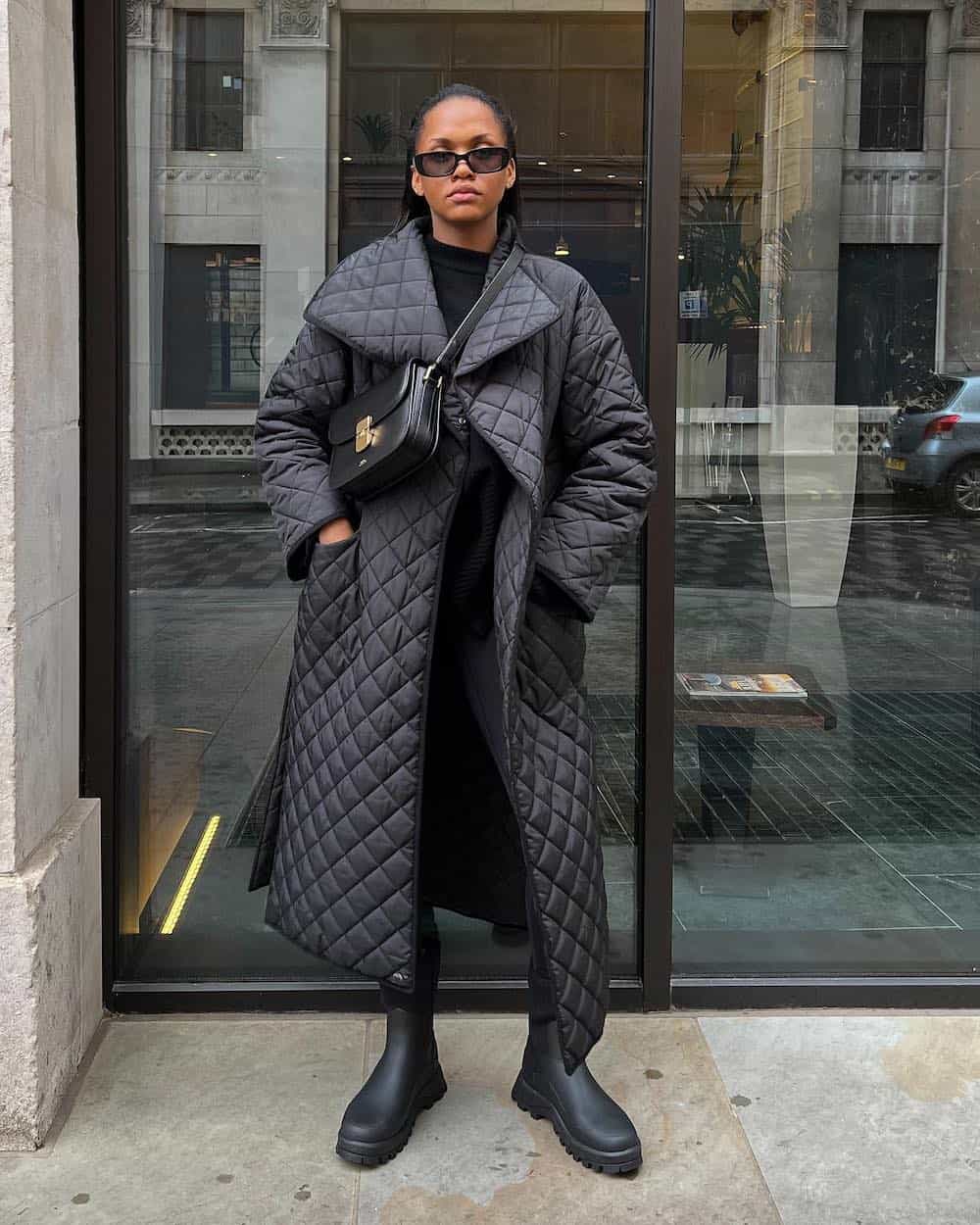 Woman wearing all black with an oversized quilted coat.
