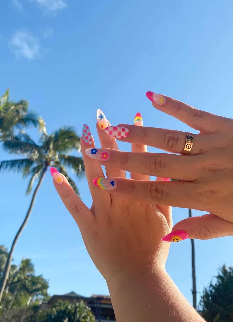 Medium almond nails with colorful retro designs including flowers, checkerboard, striped Frenchies, smileys, and heart details