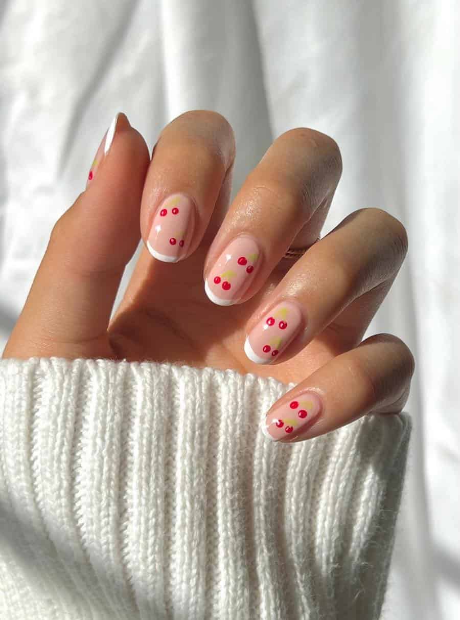 Short round beige nails with thing white tips and cherry nail art