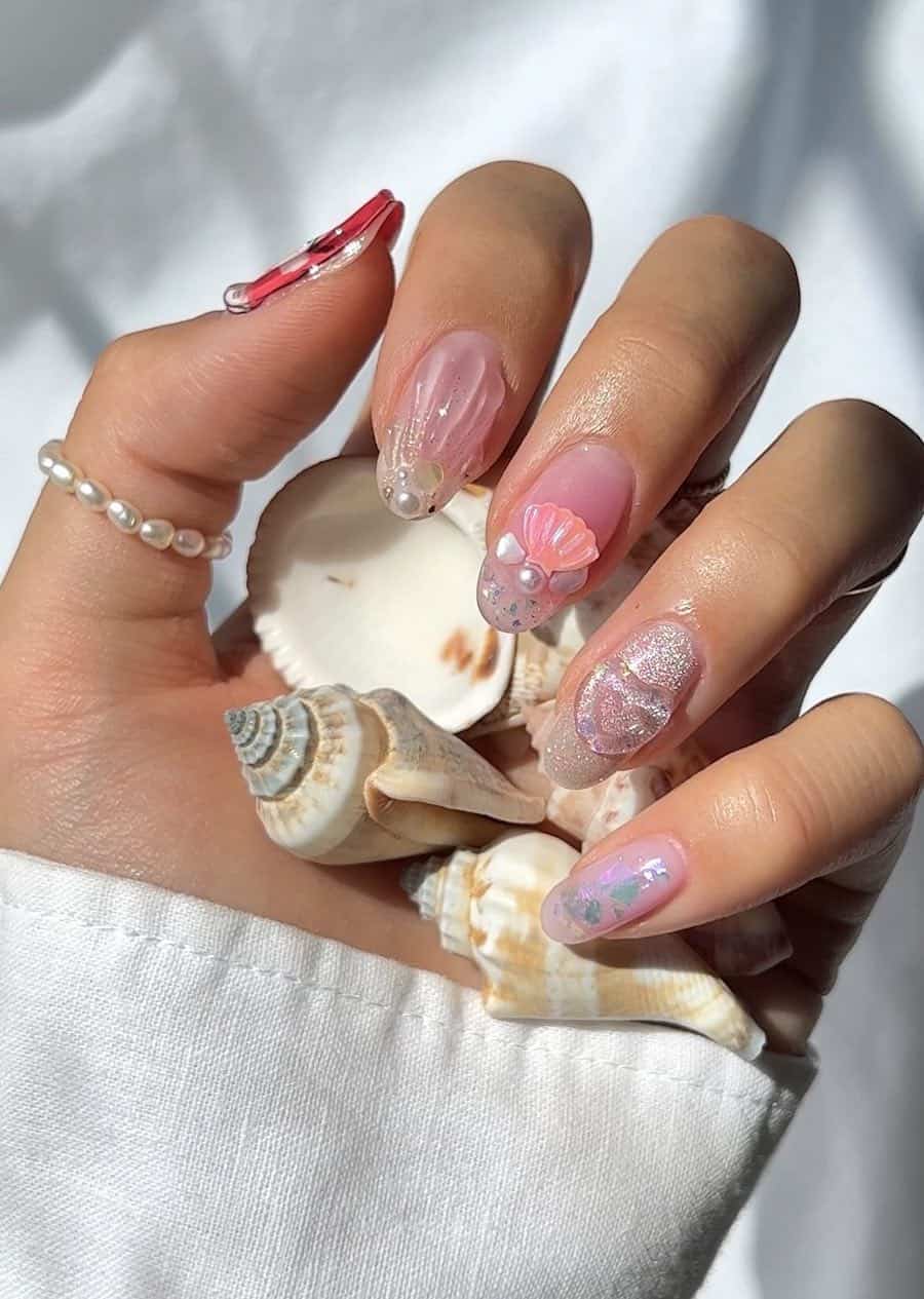 Short nude pink round nails with ocean-inspired nail art including seashells, sandy details, and pearls