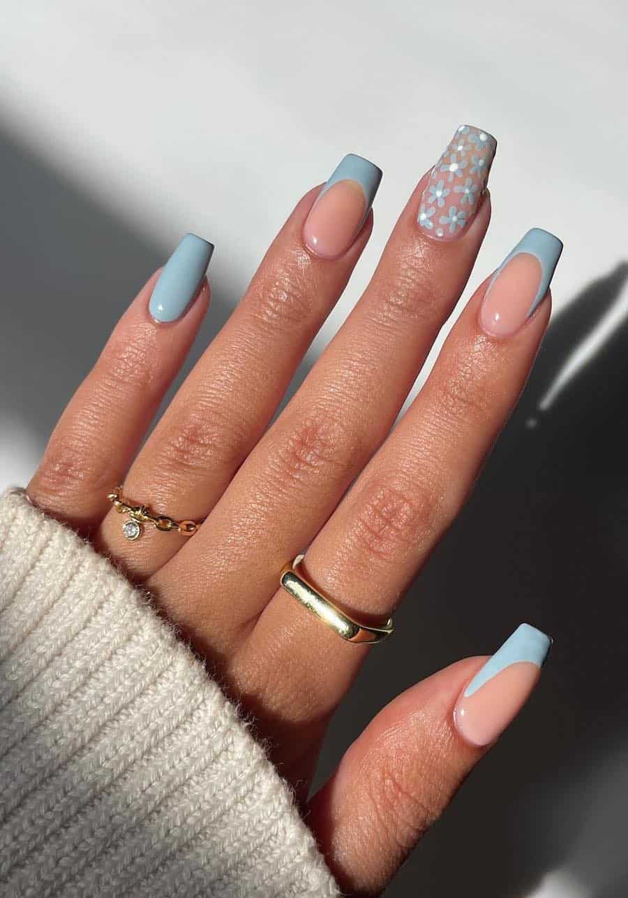 Medium coffin nails with light blue French tips, a solid-colored accent nail, and a floral art accent nail