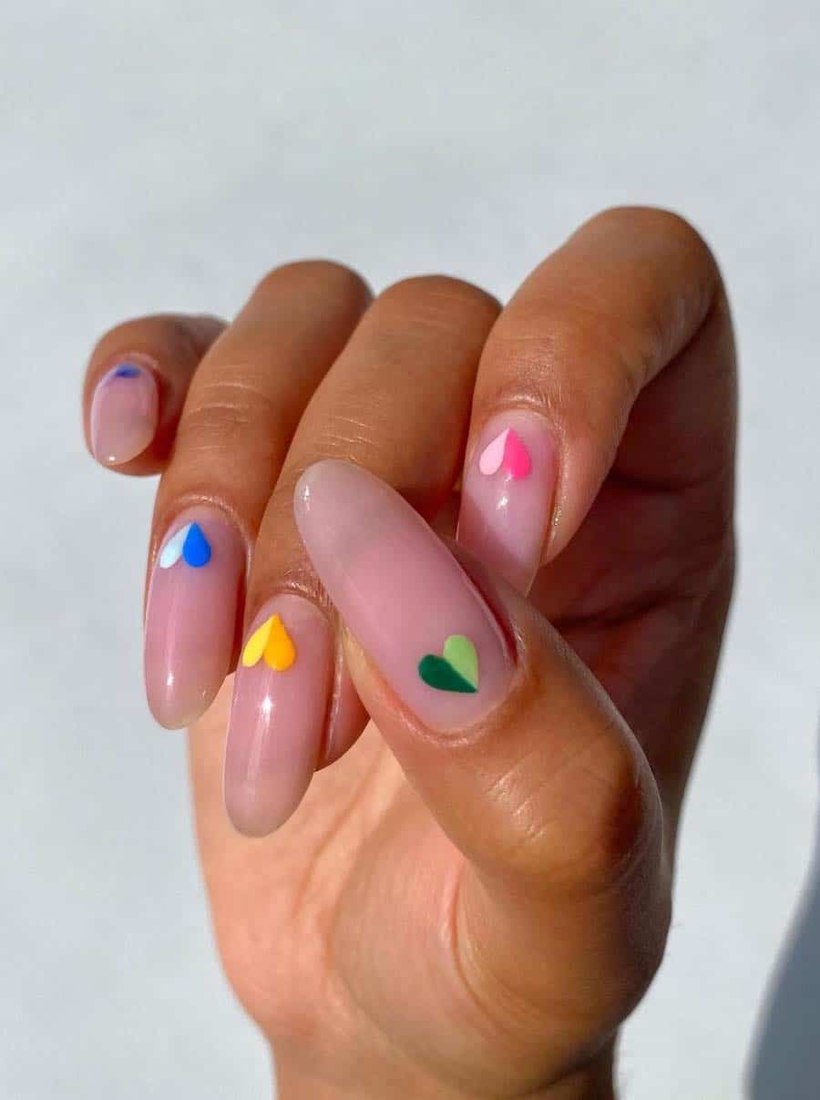 Long glossy nude almond nails with colorful two-tone hearts at the base of the nail