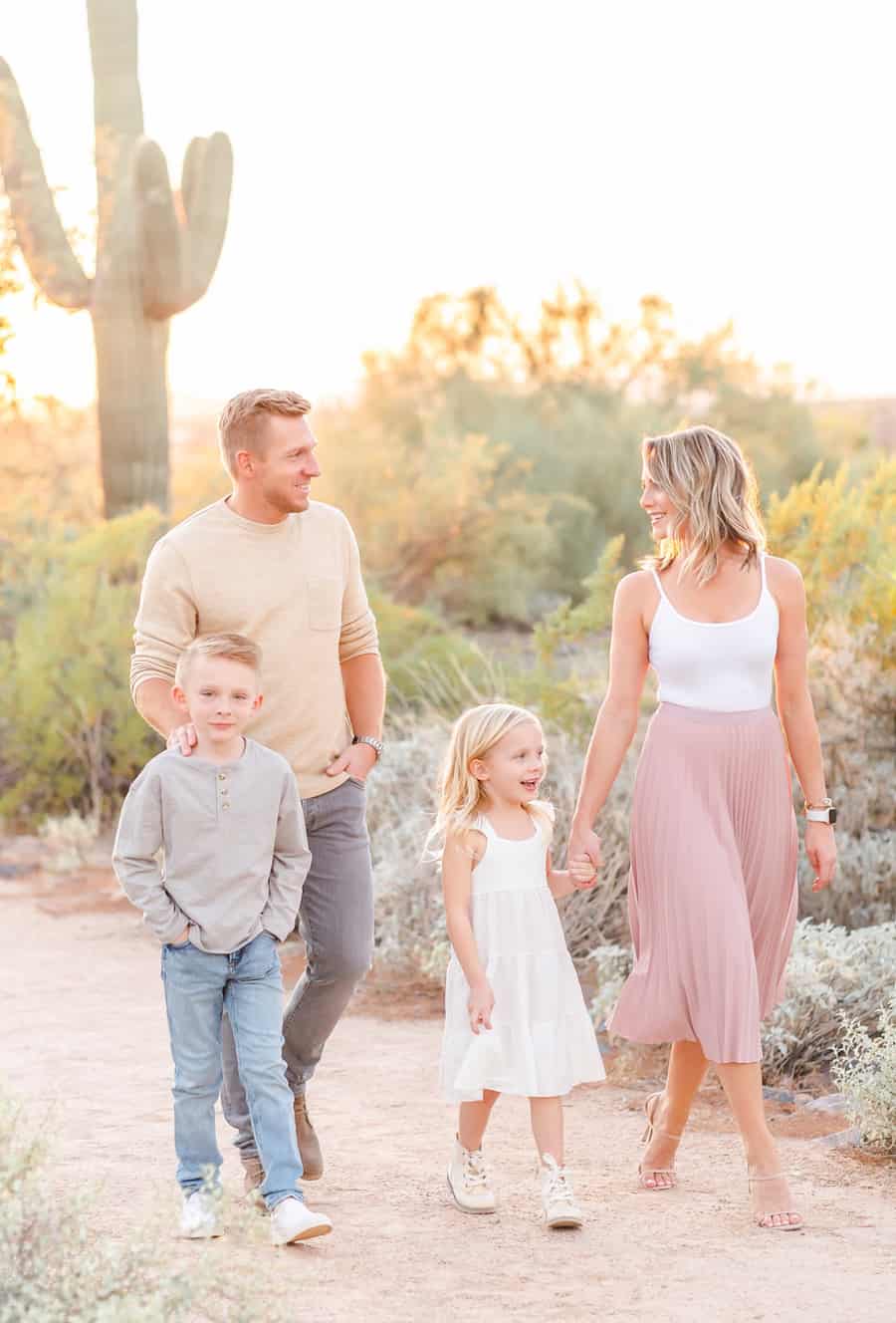 A spring family photoshoot for a family of four featuring causal clothes like a midi skirt and tank, a white midi dress, and jeans and sweaters