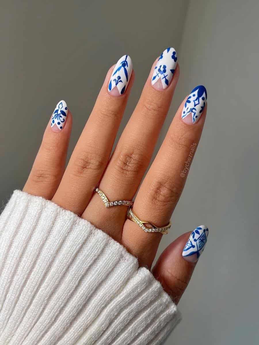 Short almond nails with blue porcelain nails with negative space v's at the bottom of the nail