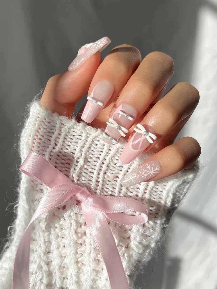 Long coffin nails with a balletcore design featuring ribbons, bows, snowflakes, and pink French tips