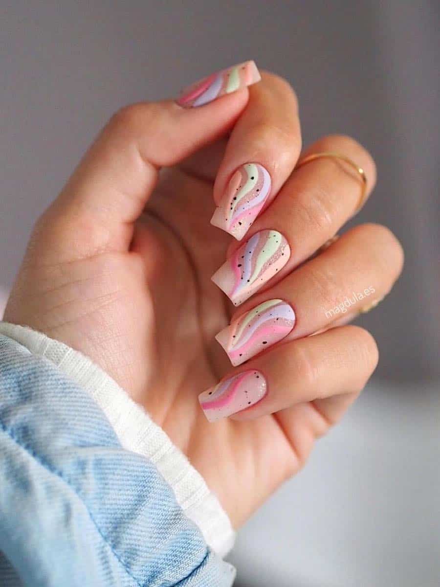 Medium square nude nails with pastel waves and black speckles with a matte finish