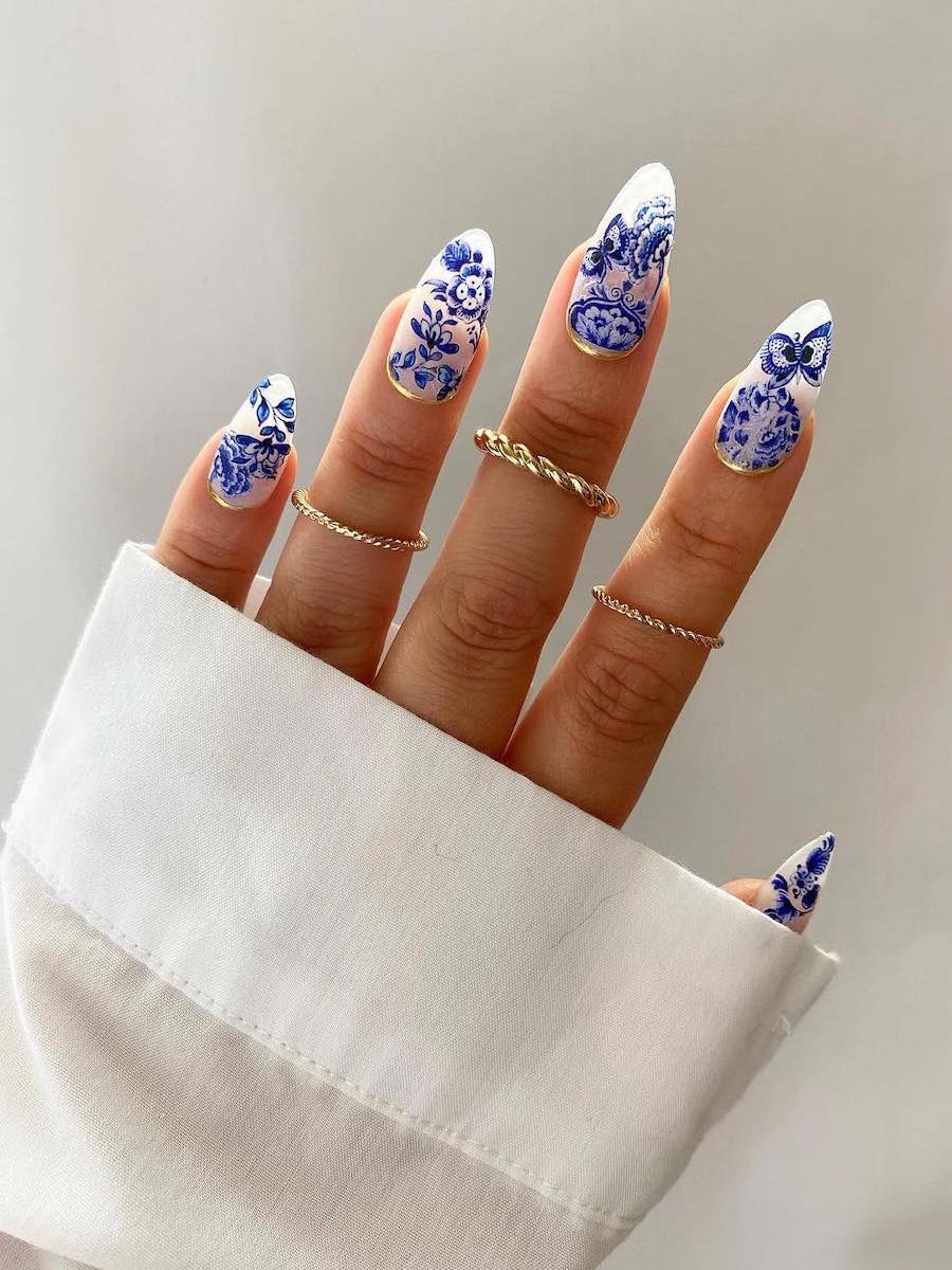 Long almond nails with blue porcelain art and gold reverse French tips