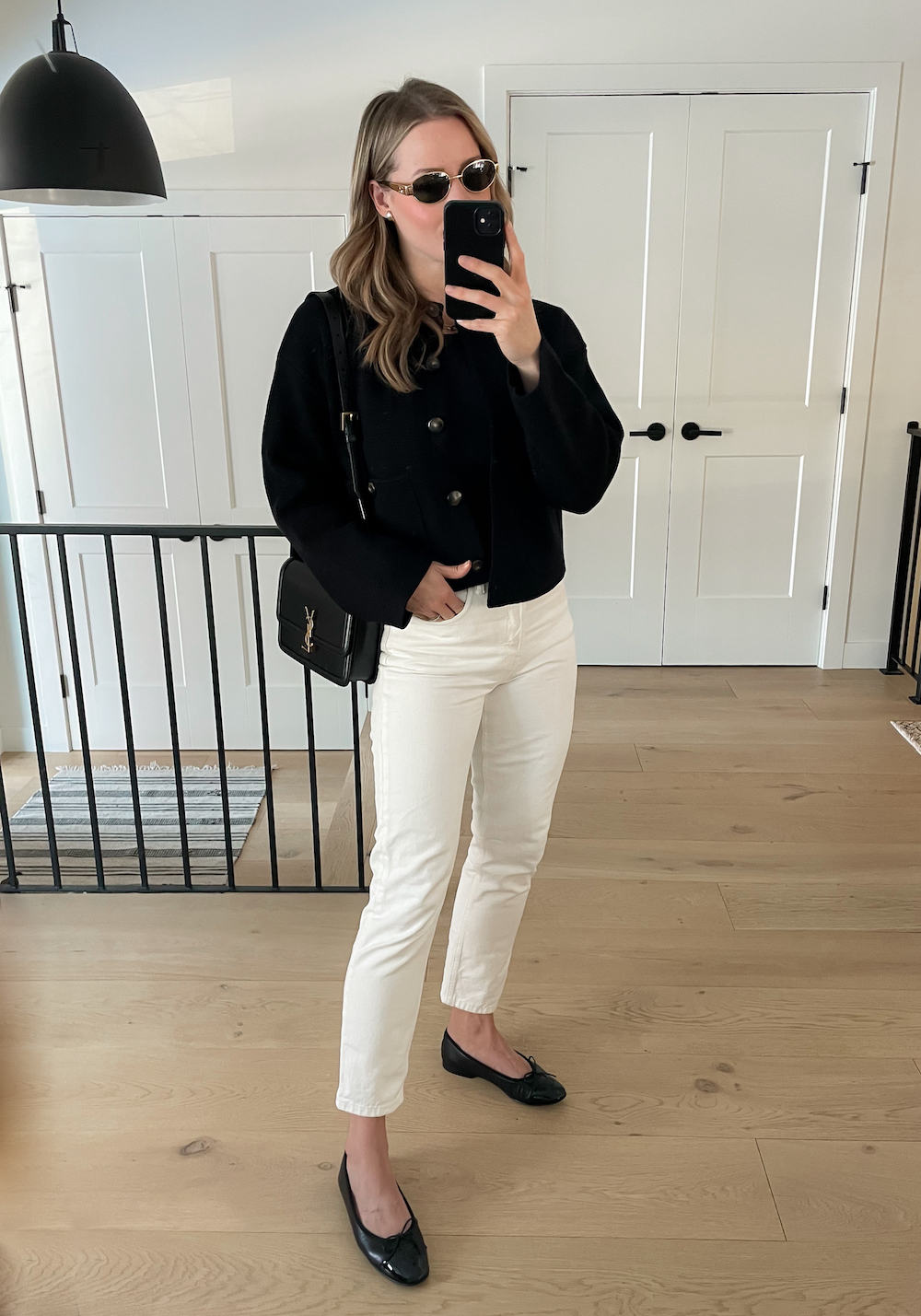 Christal wearing white jeans, black ballet flats, and a black cropped jacket with black accessories.