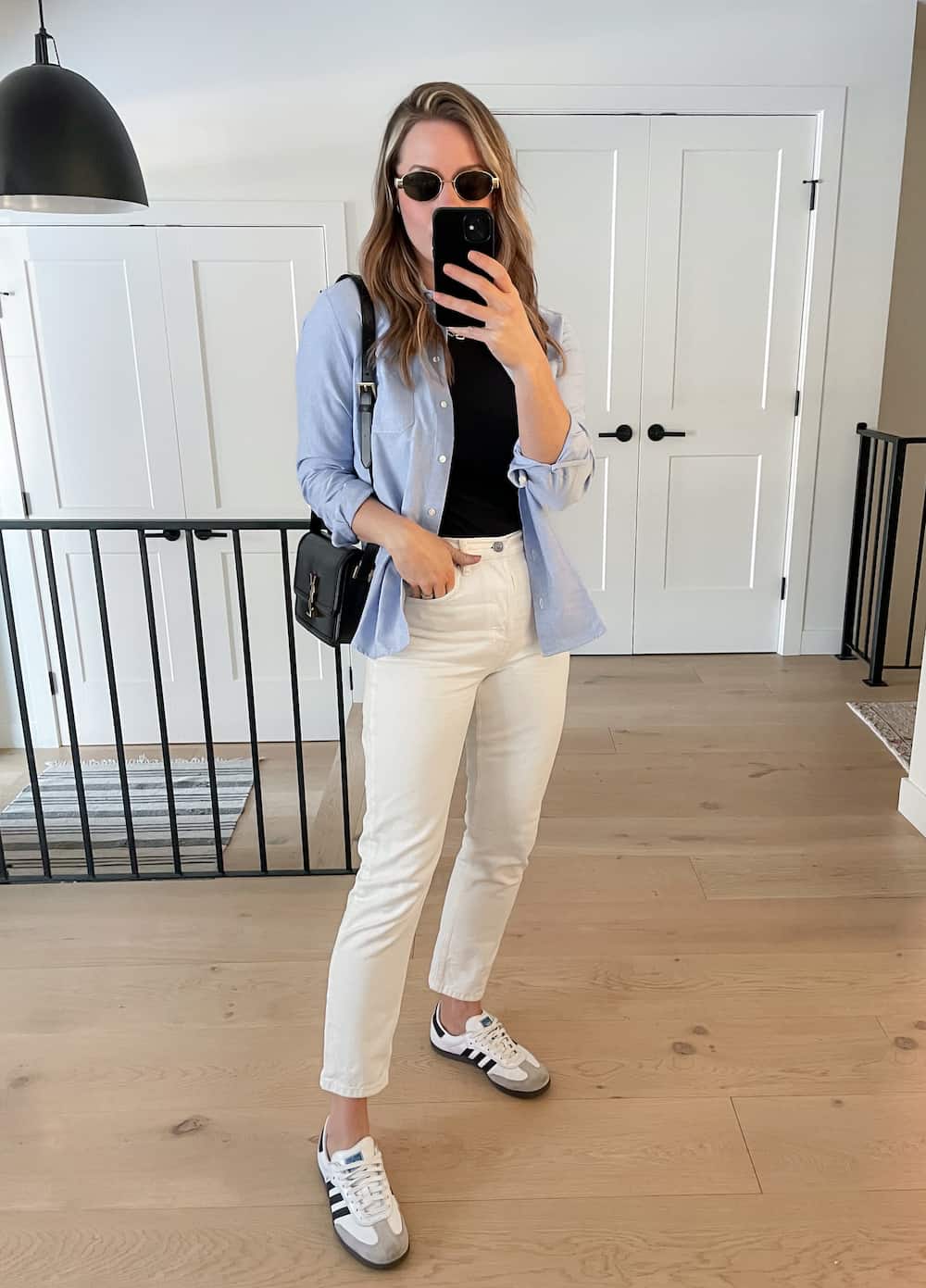 Christal wearing white jeans, a black t-shirt and a blue button down with sneakers.