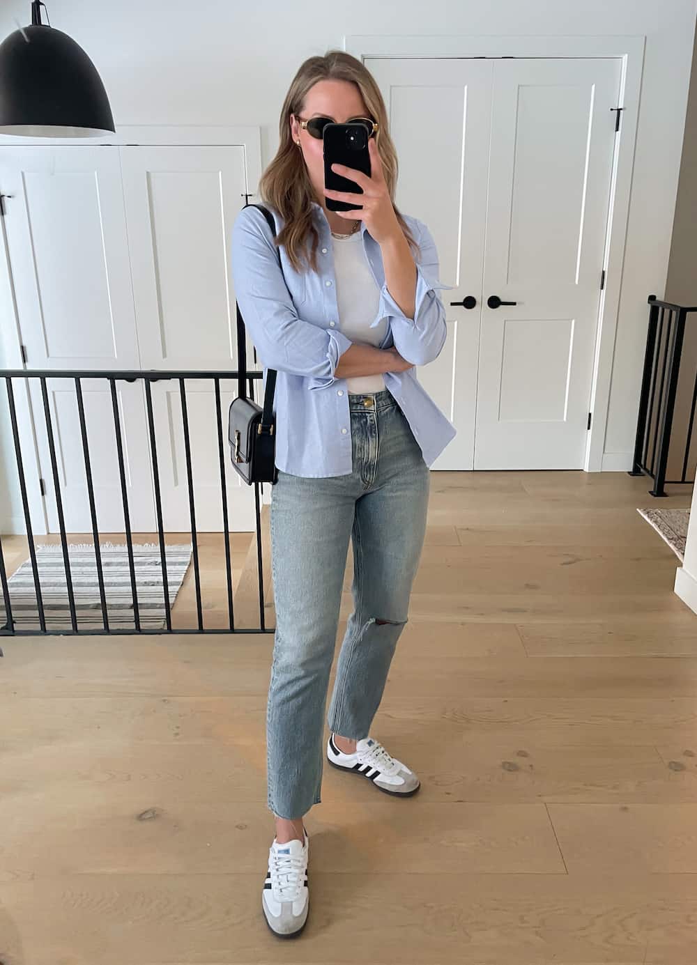 Christal wearing jeans, sneakers, a white tank top and an open blue button down.