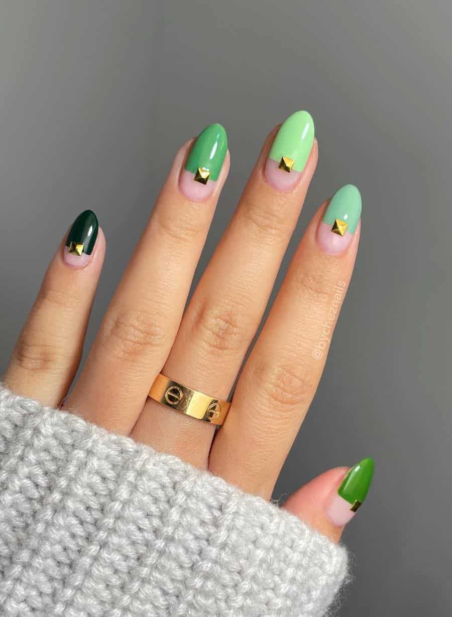 Short almond nails with a nude bottom and gradient green tops with gold gems