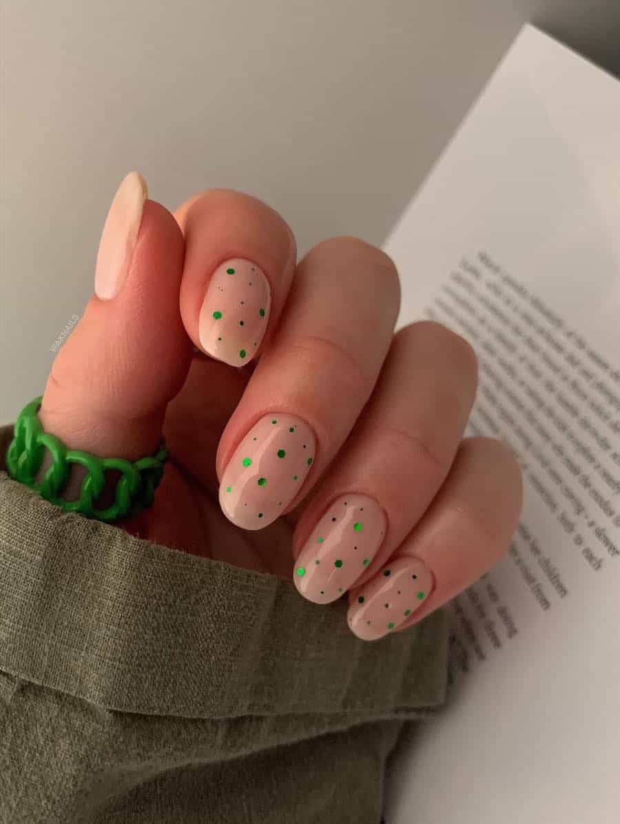 Short round nude nails with green crystals