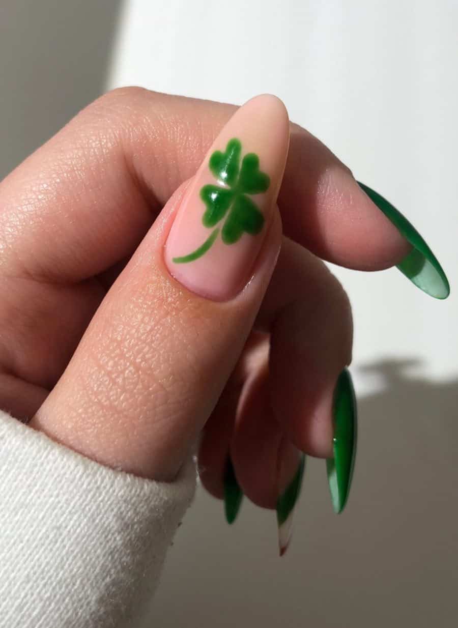 Long green almond nails with a nude accent nail featuring a green clover