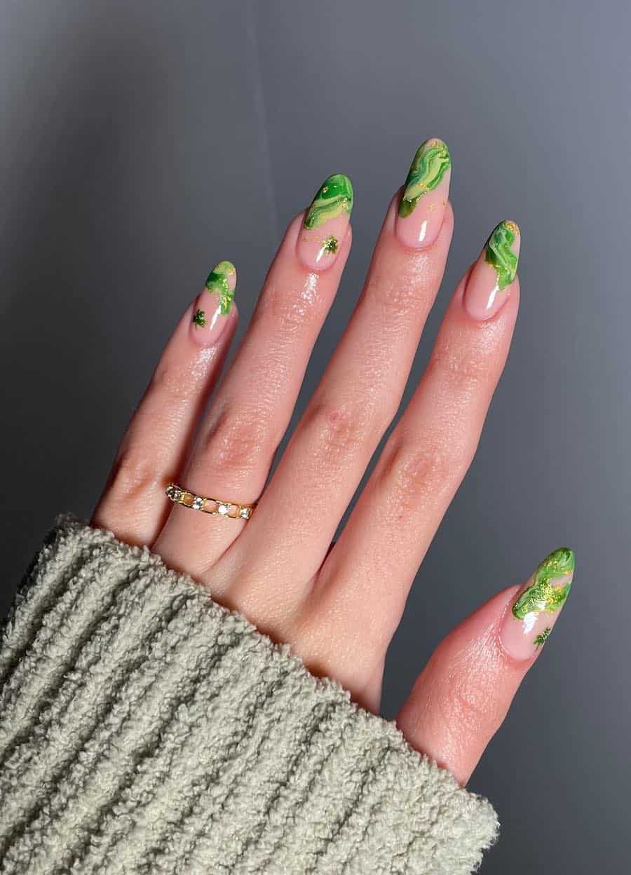 Long nude almond nails with marbled green swirls and glittering green clovers