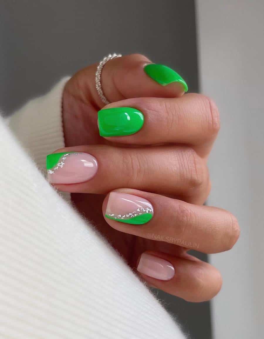 Short square nails with light green polish solid nails and nude nails and two accent nails with green waves with silver foil borders