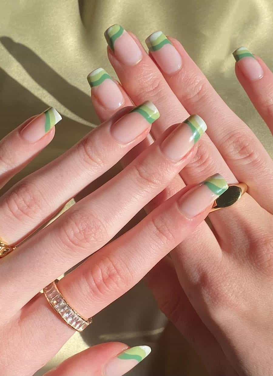 Medium nude coffin nails with waves of dark green, light green, and white tips