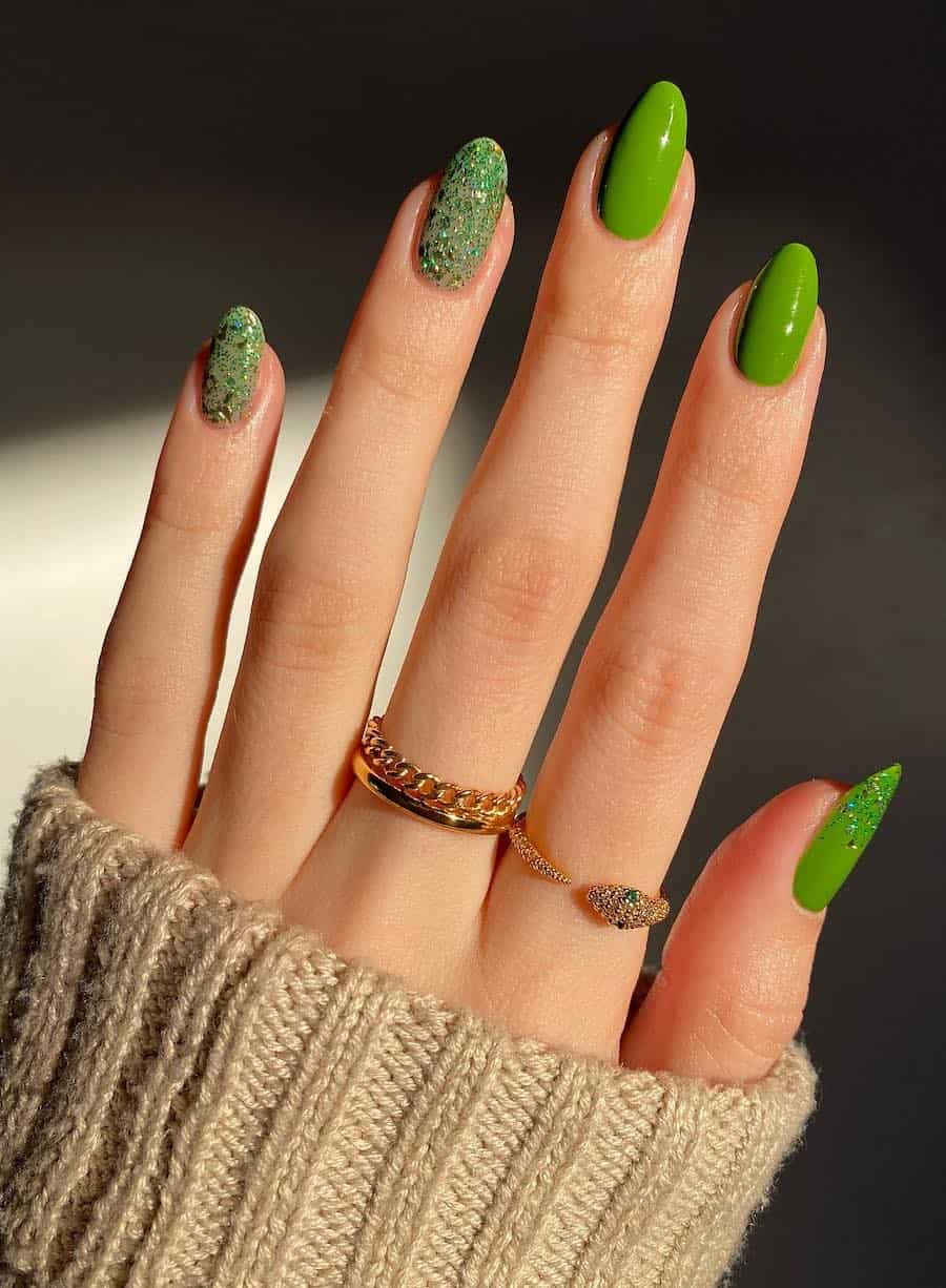 Medium almond nails with solid green nail polish and green glitter accent nails
