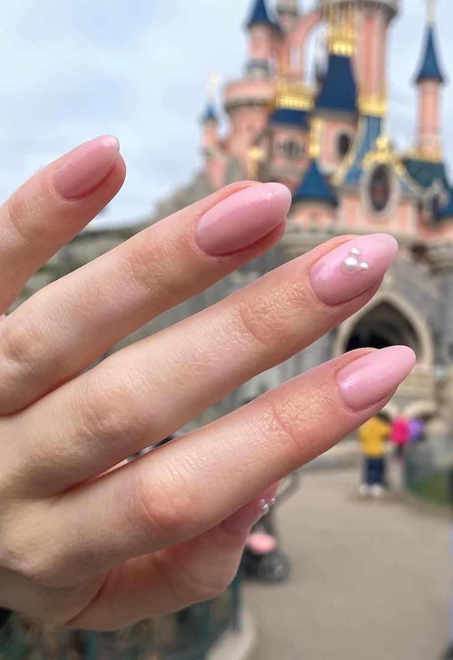 Medium almond nails with a Mickey Mouse design featuring soft pink polish and pearl accents