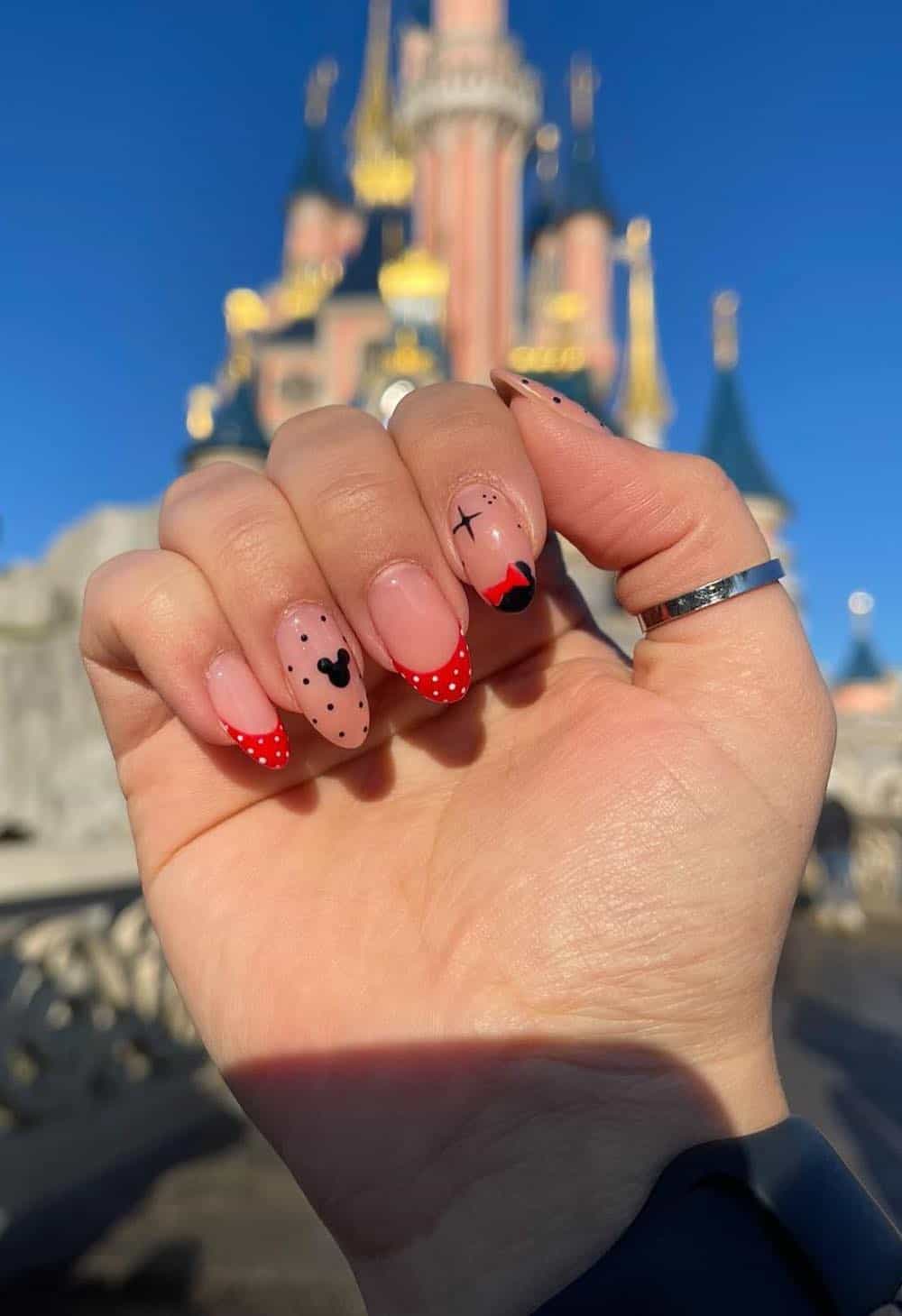 Medium round nails with a Mickey Mouse design featuring nude nails with red and black designs