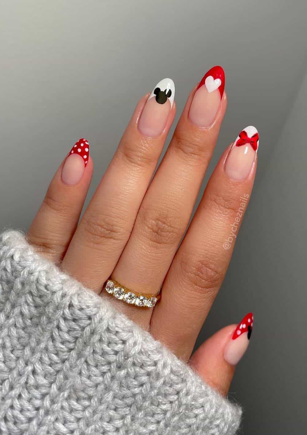 Medium almond nails with a Mickey Mouse design featuring nude polish, white and red tips, and simple accents