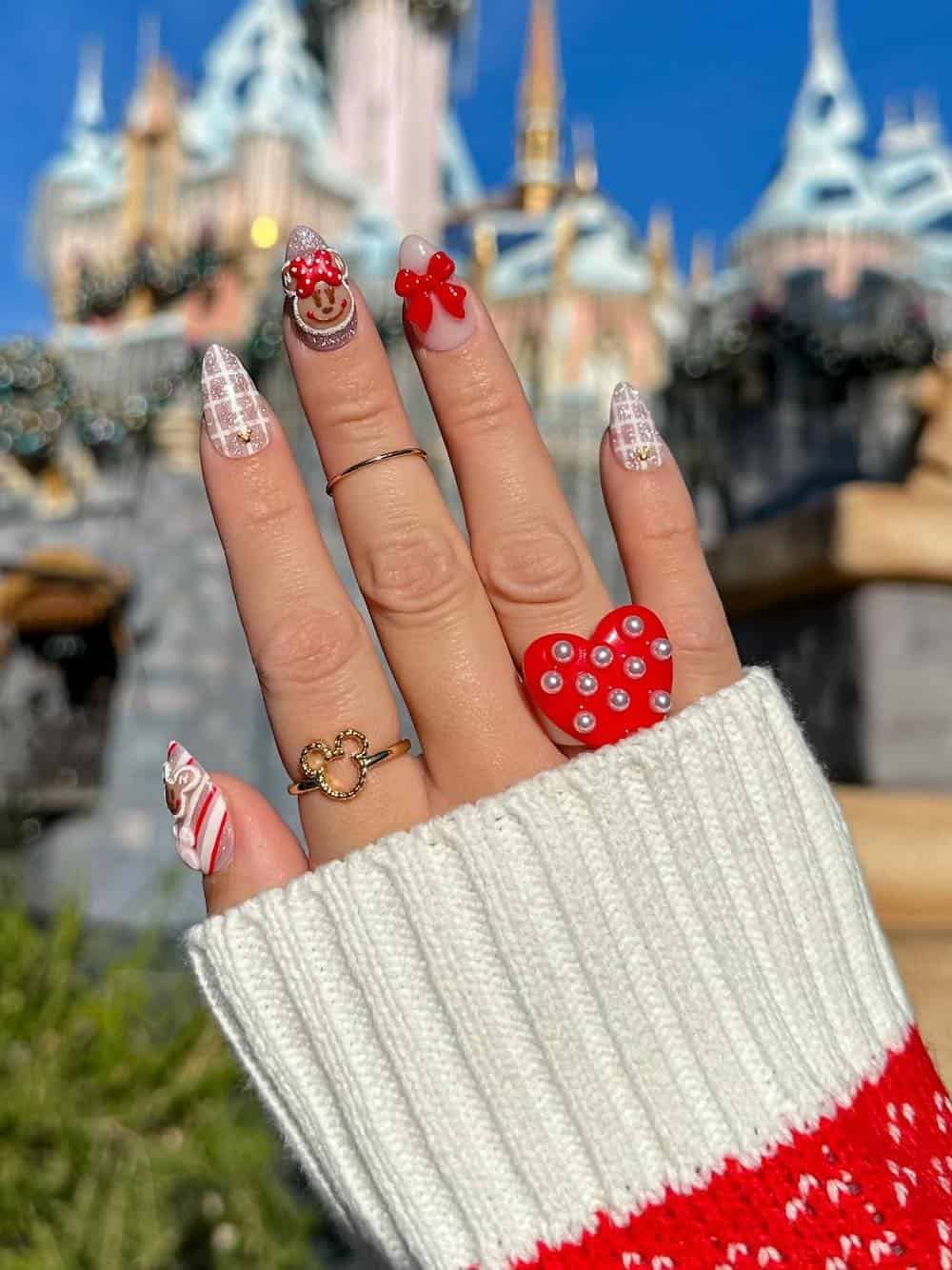 Medium almond nails with a Christmas Mickey Mouse design featuring white nude, and red polish and gingerbread art