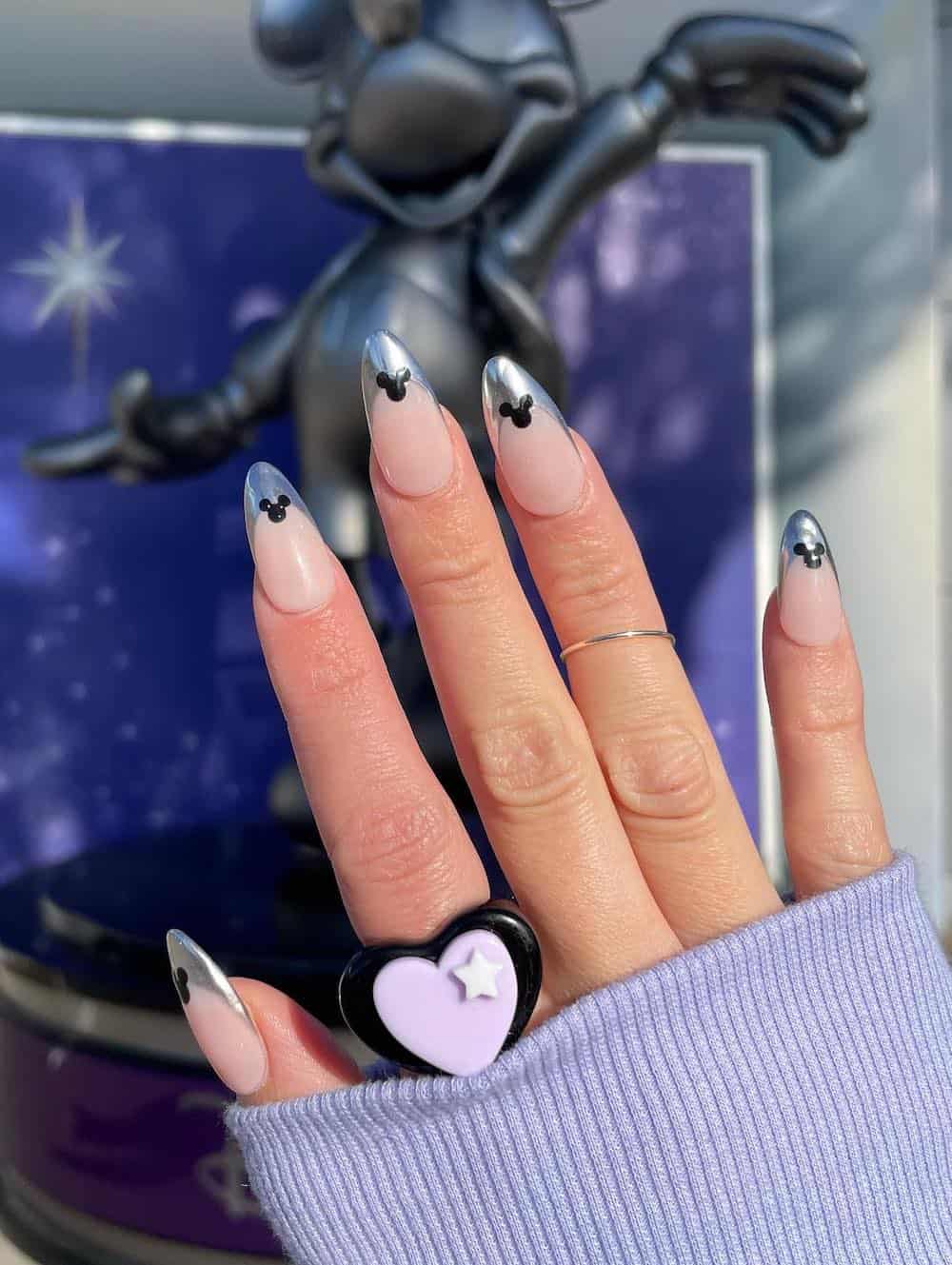 Medium almond nails with a Mickey Mouse design featuring metallic silver tips and black Mickey silhouettes